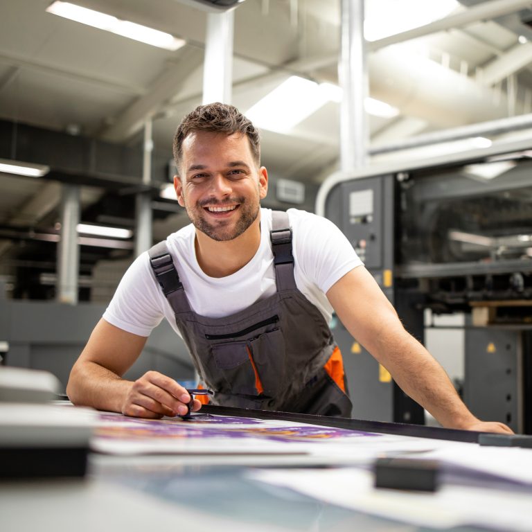 Portrait of worker at control room checking print quality at printing house.