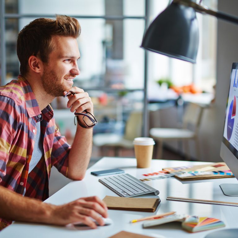 Happy man looking at computer screen with data while making final decision