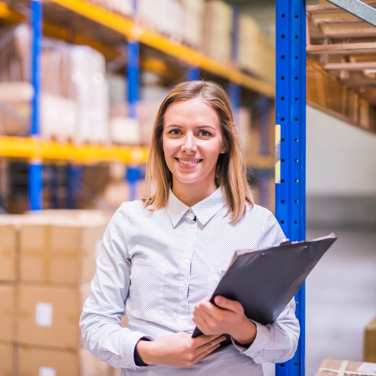 Portrait of a young woman warehouse worker or supervisor with clipboard.
